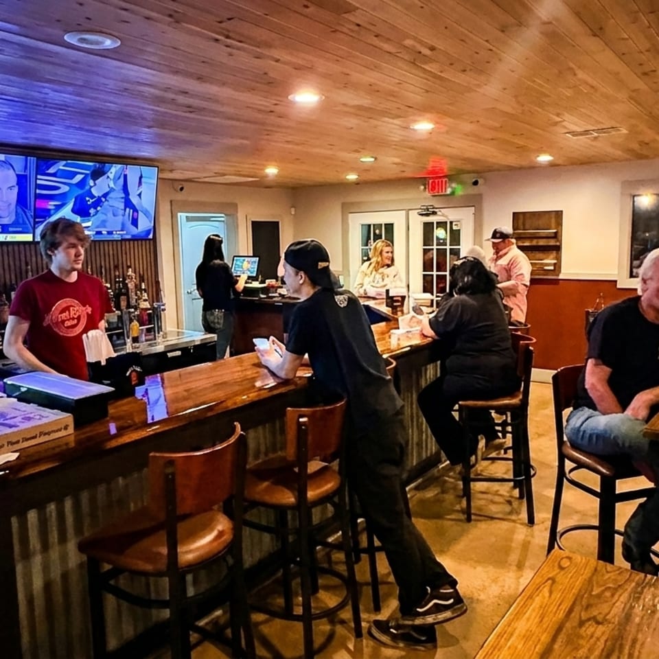 A lively bar scene with patrons seated at the bar and tables, enjoying drinks and conversation.