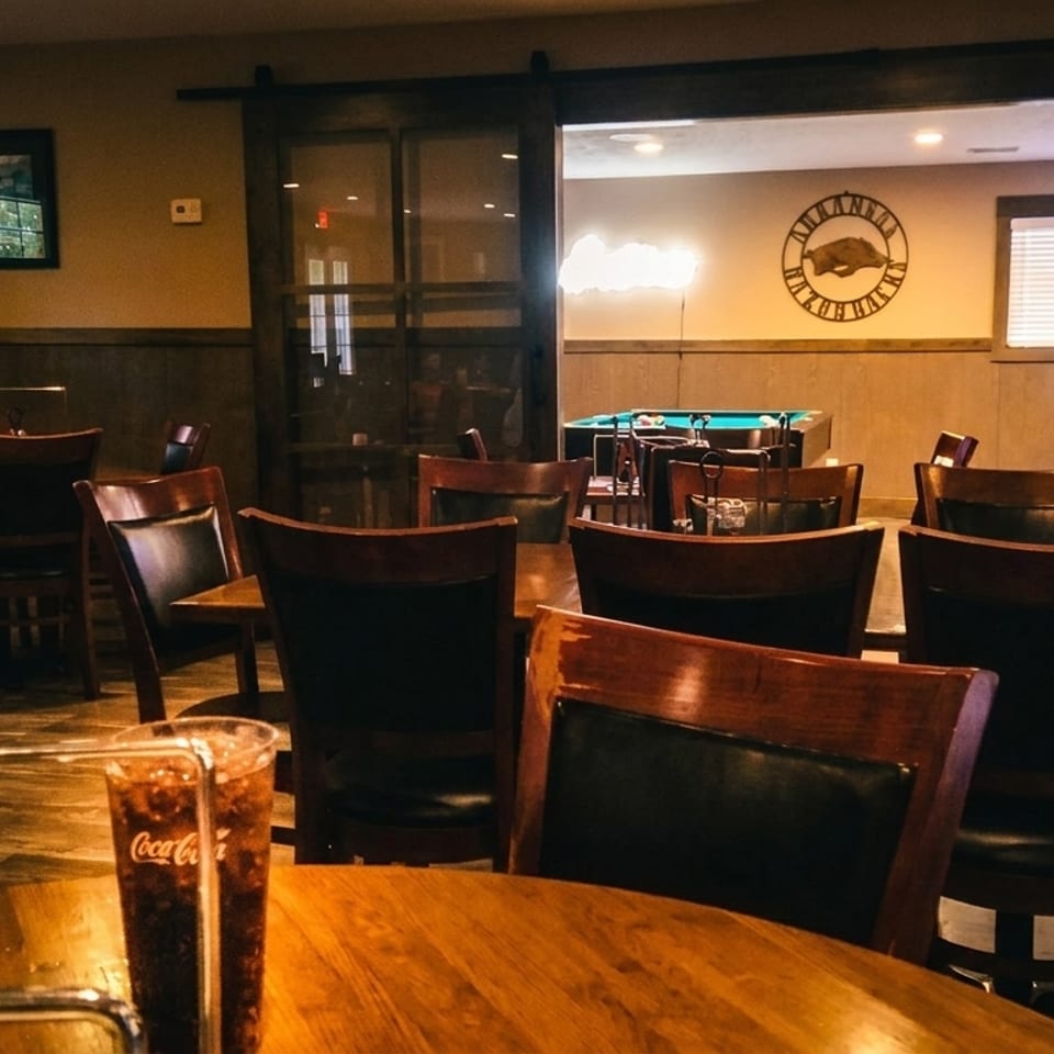 Restaurant dining area with wooden tables and chairs, a menu, and a Coca-Cola drink.